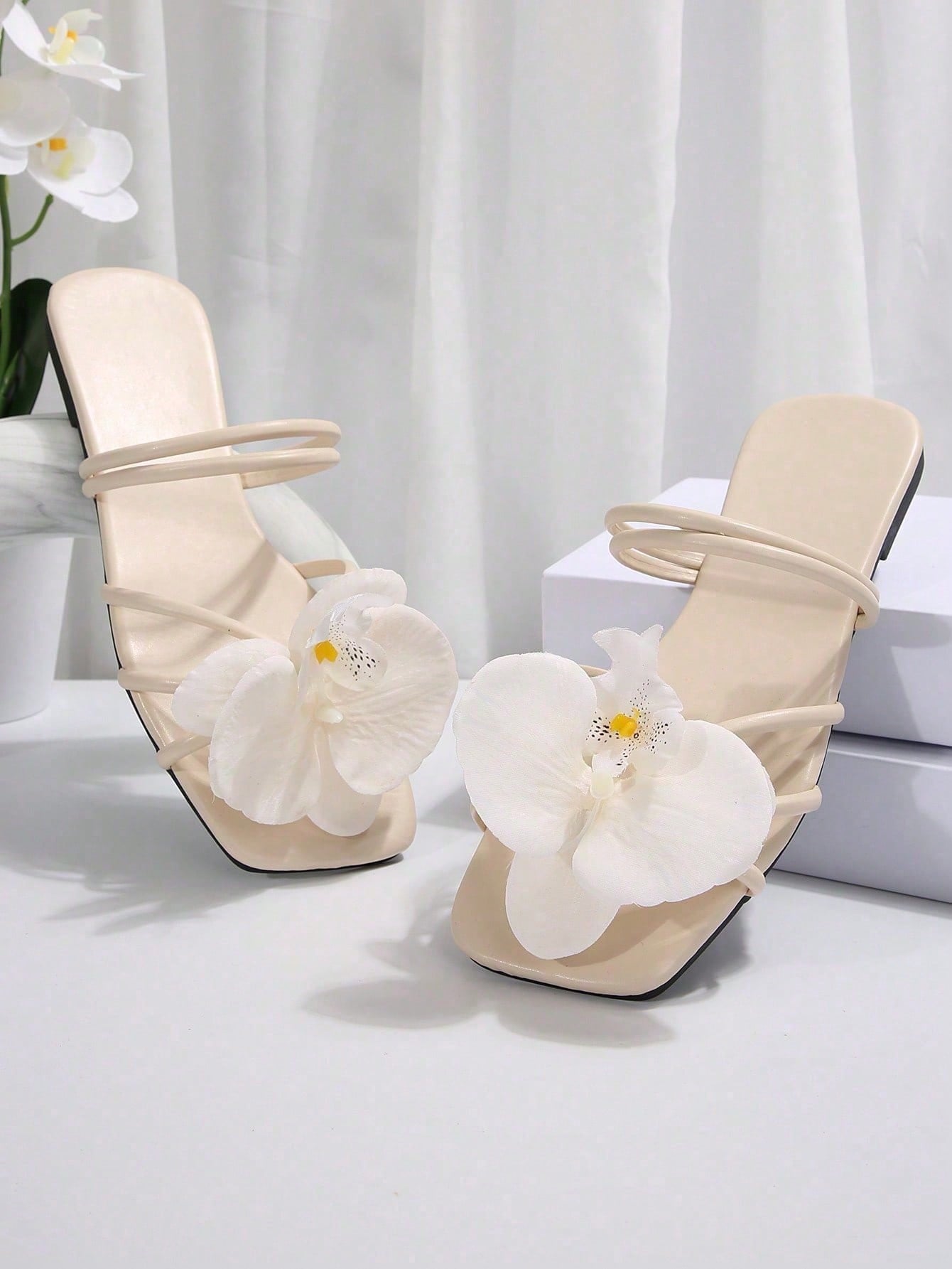 Women's flat slide sandals with open toe, floral applique detail, and criss-cross straps, shown as casual vacation-style summer footwear.