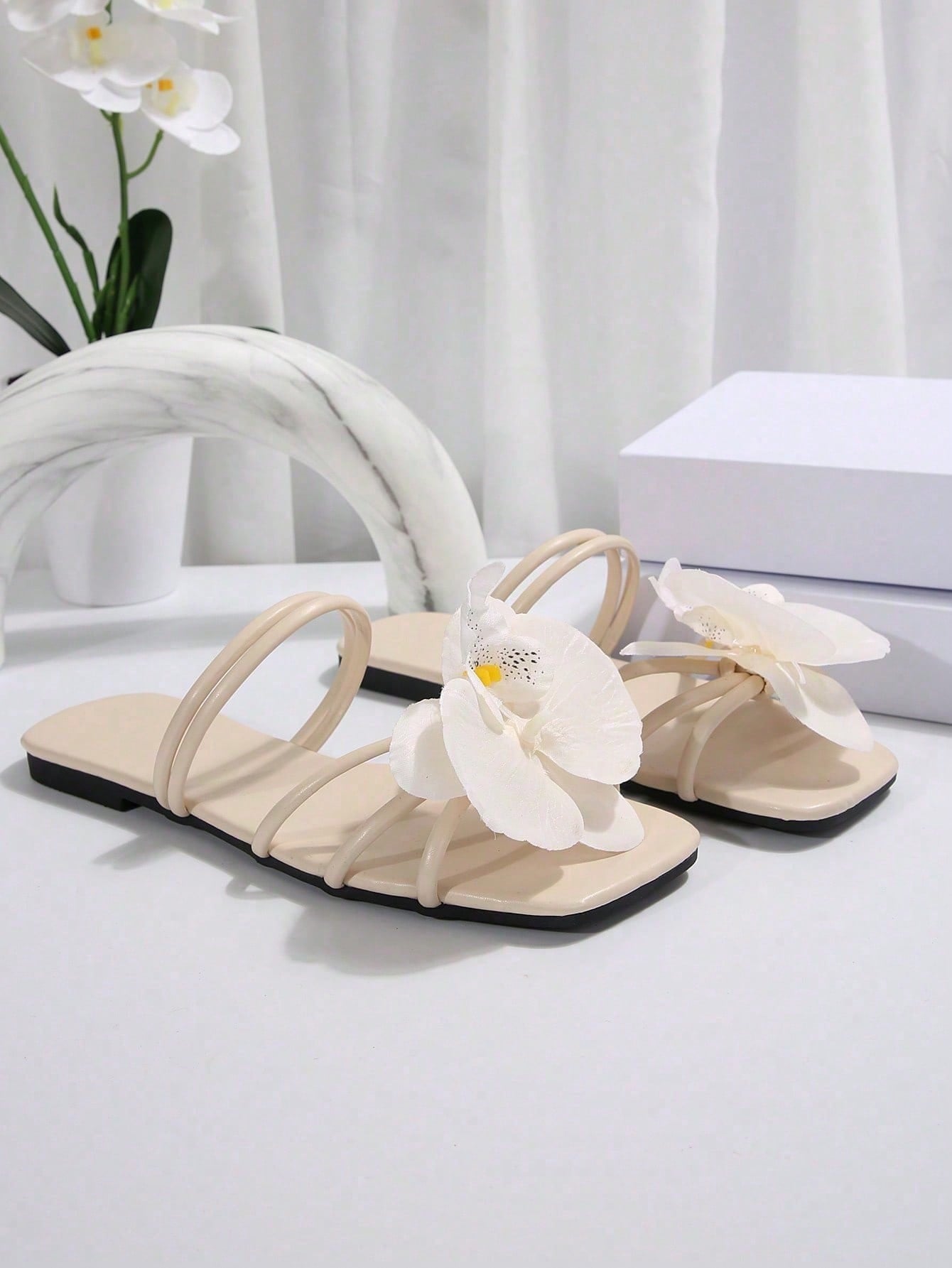 Women's flat slide sandals with open toe, floral applique detail, and criss-cross straps, shown as casual vacation-style summer footwear.