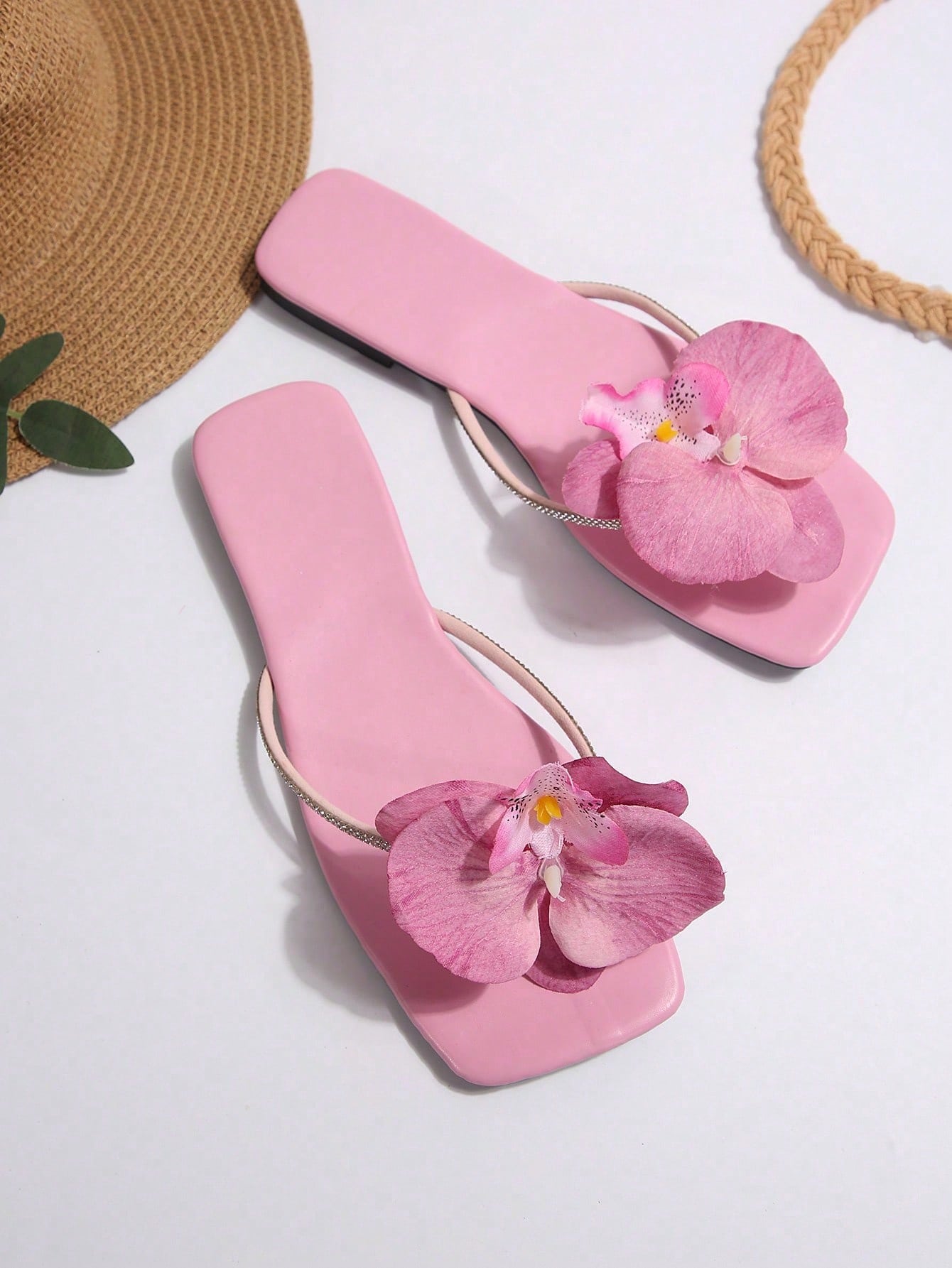 Women's flat slide sandals with open toe, floral applique detail, and criss-cross straps, shown as casual vacation-style summer footwear.