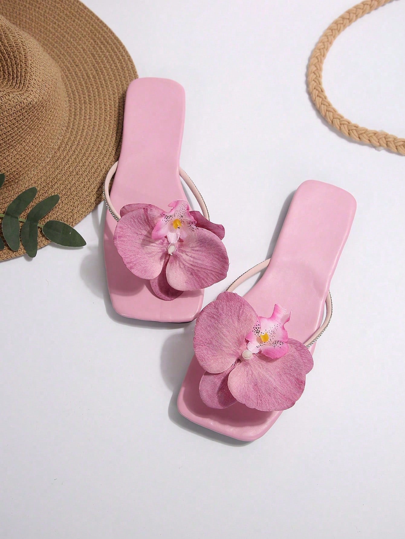 Women's flat slide sandals with open toe, floral applique detail, and criss-cross straps, shown as casual vacation-style summer footwear.
