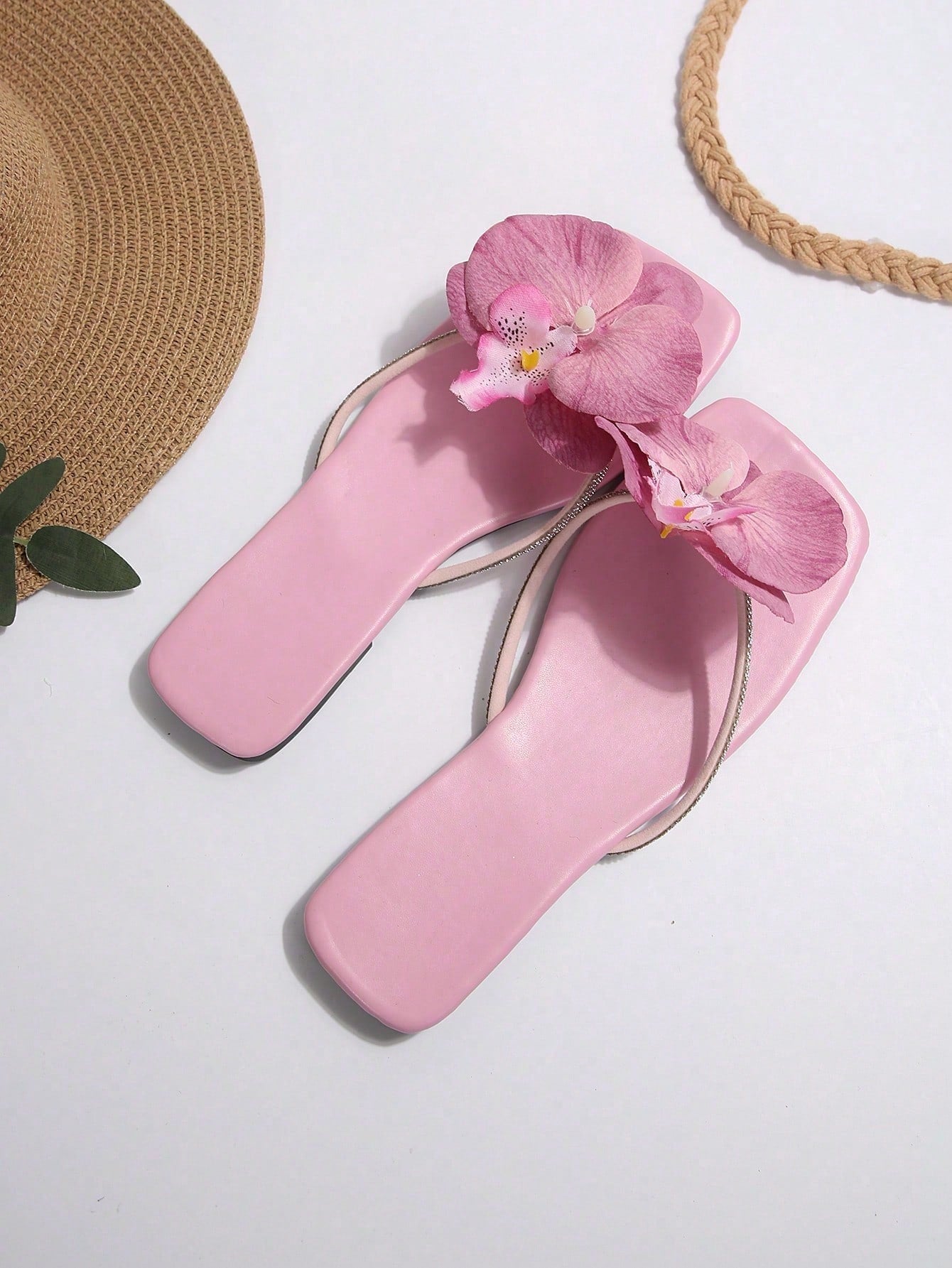 Women's flat slide sandals with open toe, floral applique detail, and criss-cross straps, shown as casual vacation-style summer footwear.