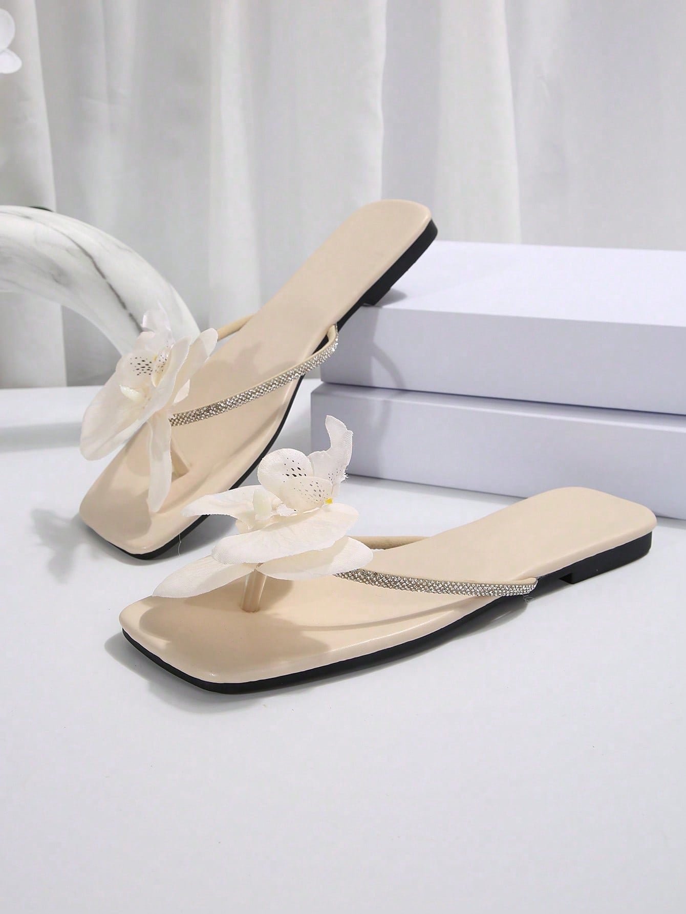 Women's flat slide sandals with open toe, floral applique detail, and criss-cross straps, shown as casual vacation-style summer footwear.