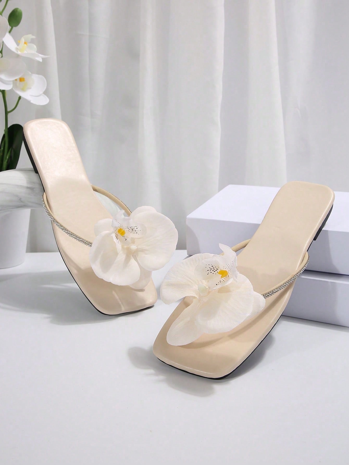 Women's flat slide sandals with open toe, floral applique detail, and criss-cross straps, shown as casual vacation-style summer footwear.