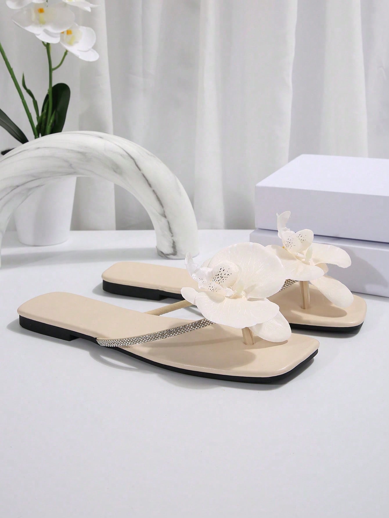 Women's flat slide sandals with open toe, floral applique detail, and criss-cross straps, shown as casual vacation-style summer footwear.