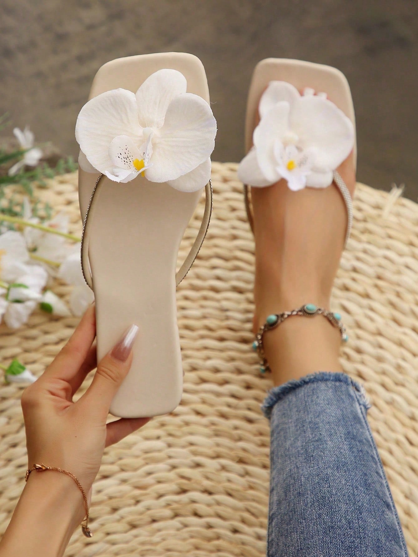 Women's flat slide sandals with open toe, floral applique detail, and criss-cross straps, shown as casual vacation-style summer footwear.