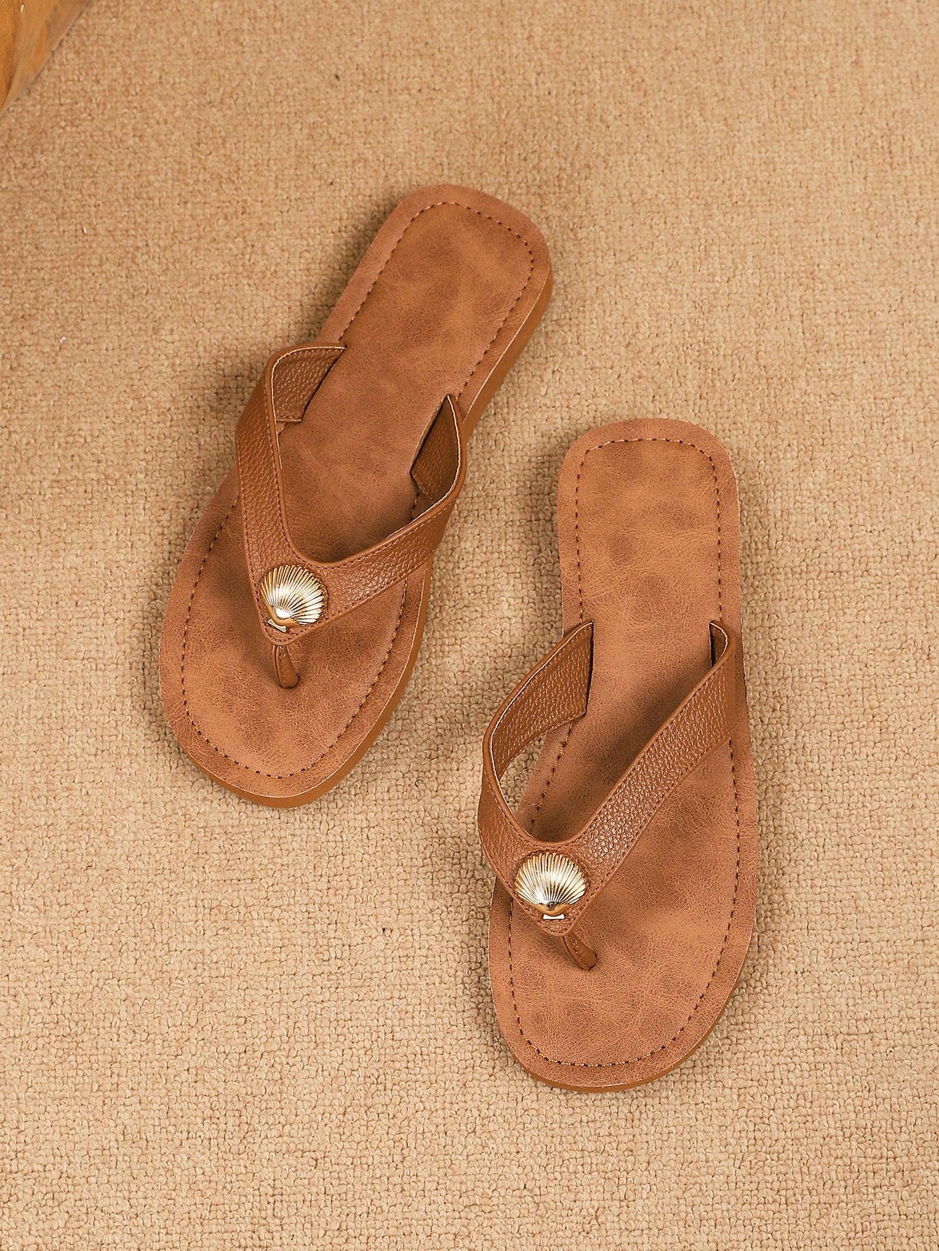 Brown vintage chic flip flops with metal shell decor, toe-post slide design, criss cross straps, and wedge sole for casual beach and outdoor wear.