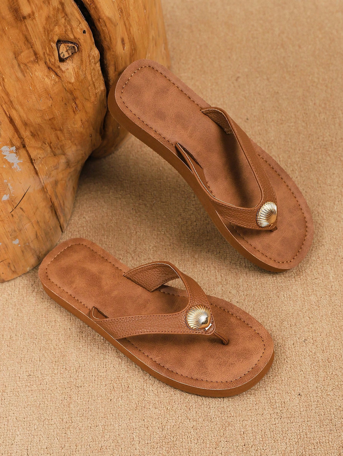 Brown vintage chic flip flops with metal shell decor, toe-post slide design, criss cross straps, and wedge sole for casual beach and outdoor wear.