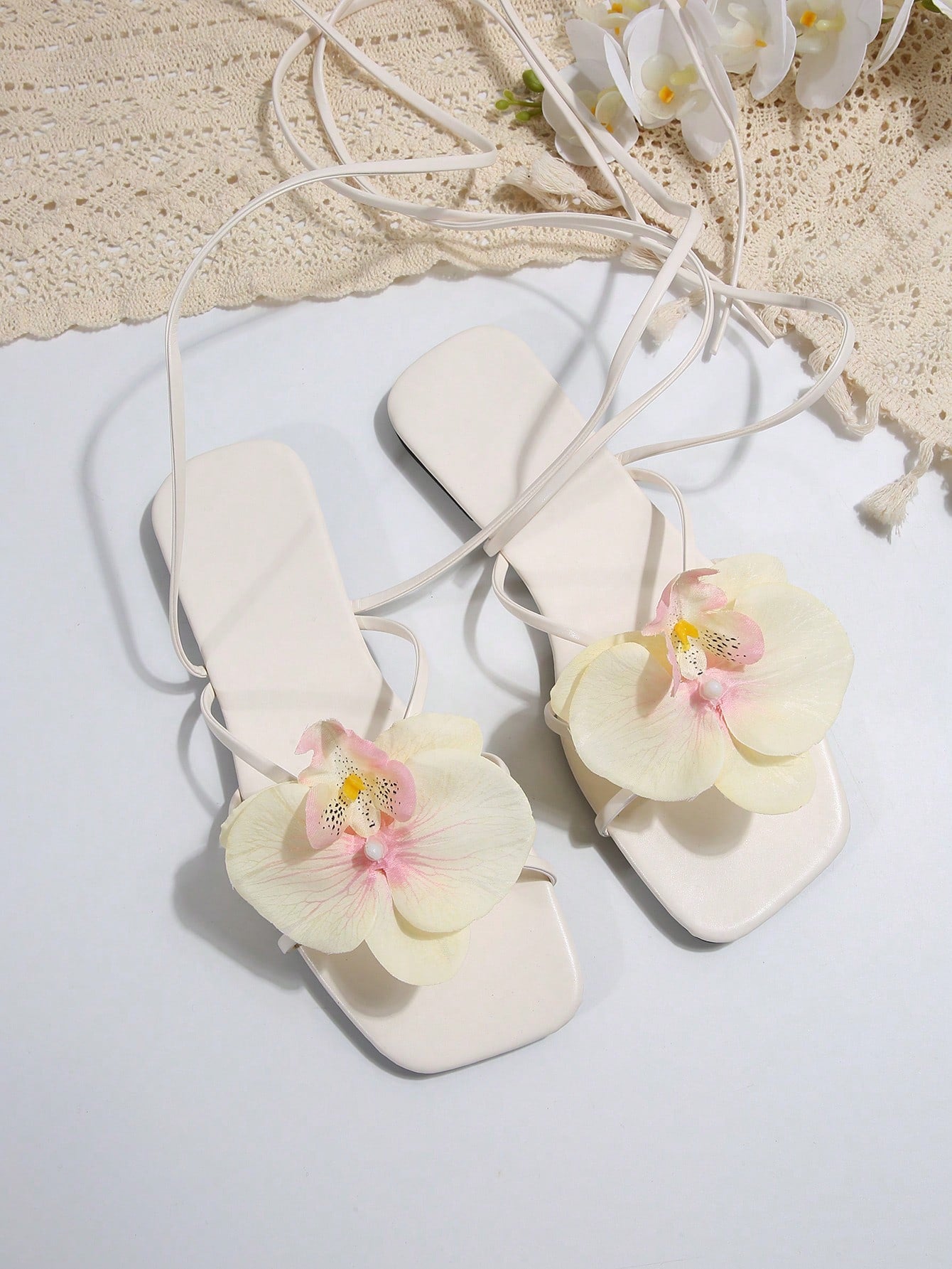 Women's flat slide sandals with open toe, floral applique detail, and criss-cross straps, shown as casual vacation-style summer footwear.
