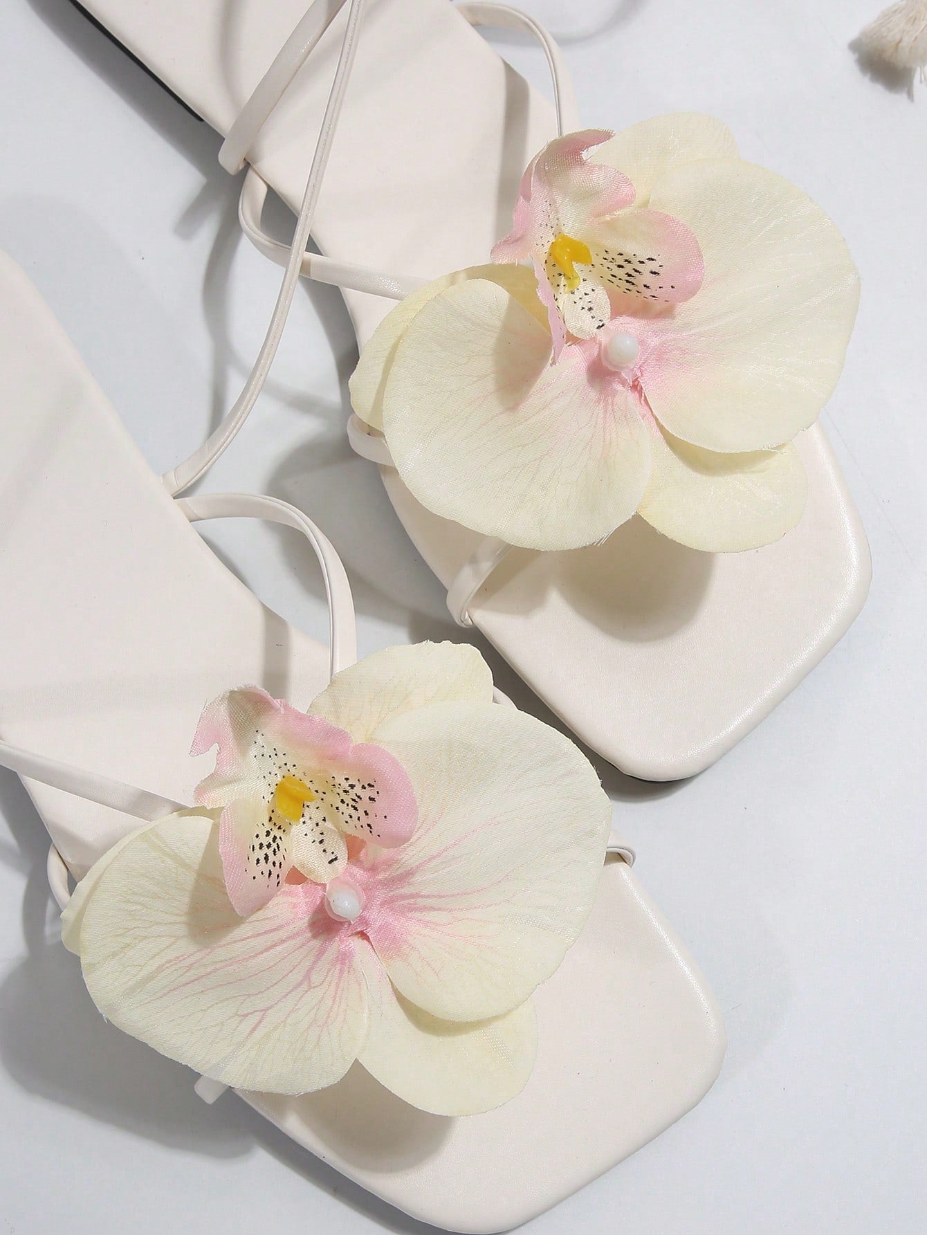 Women's flat slide sandals with open toe, floral applique detail, and criss-cross straps, shown as casual vacation-style summer footwear.