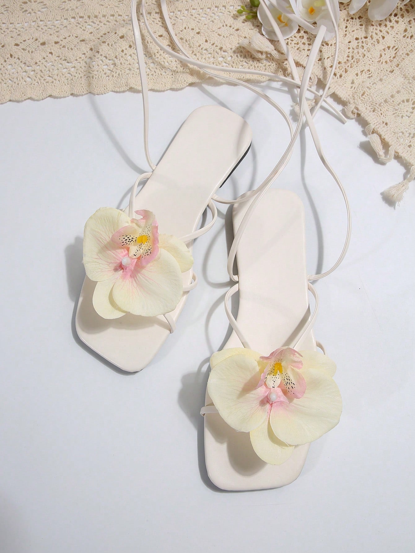 Women's flat slide sandals with open toe, floral applique detail, and criss-cross straps, shown as casual vacation-style summer footwear.