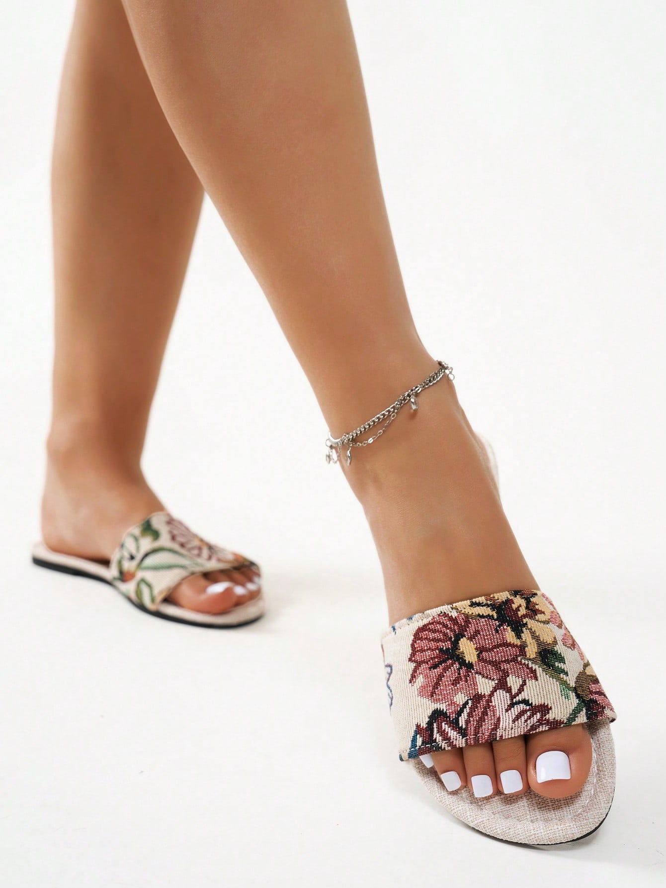 Women’s flat slide sandals featuring a floral printed strap and open toe design in a minimal style.
