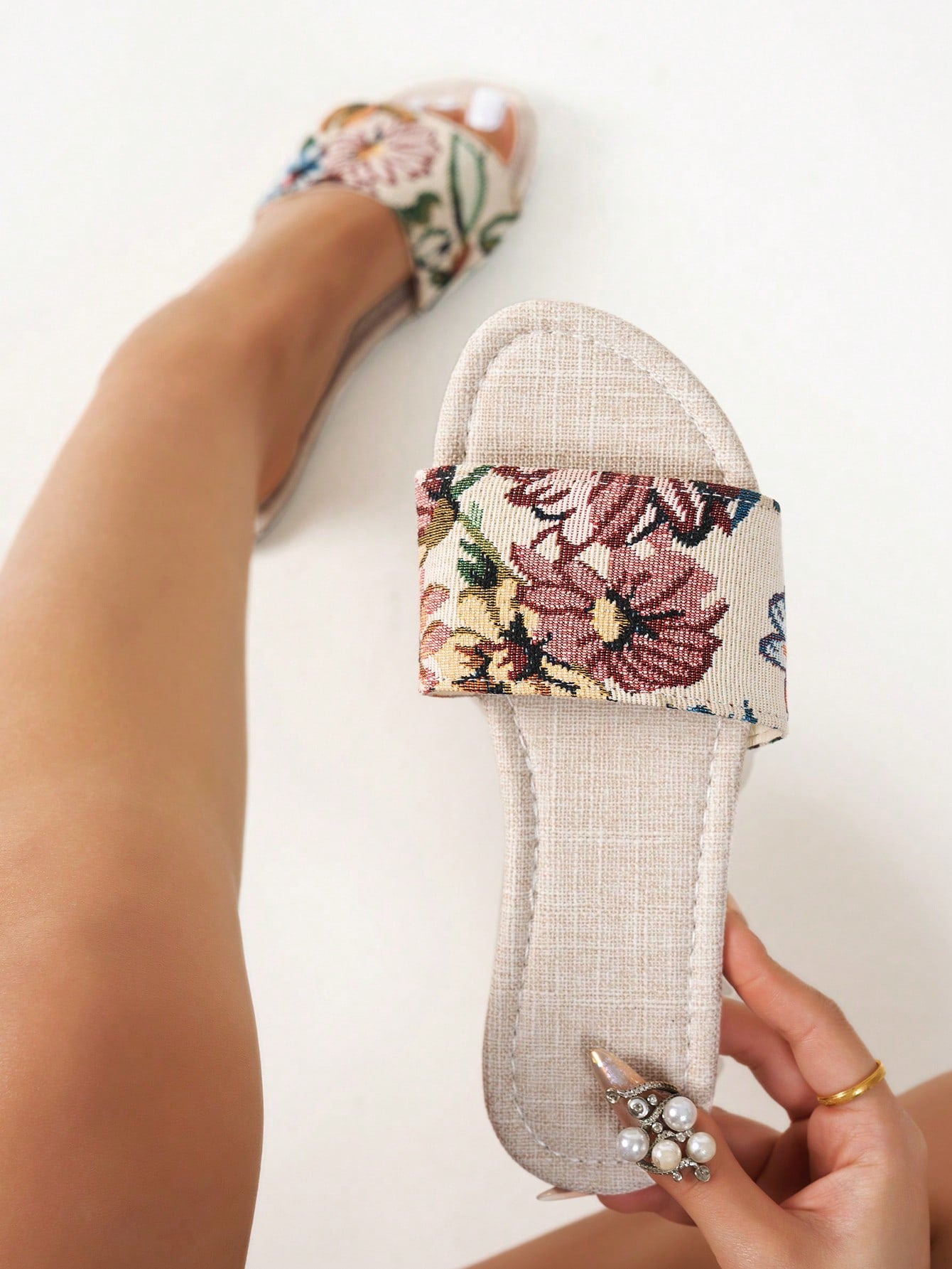 Women’s flat slide sandals featuring a floral printed strap and open toe design in a minimal style.