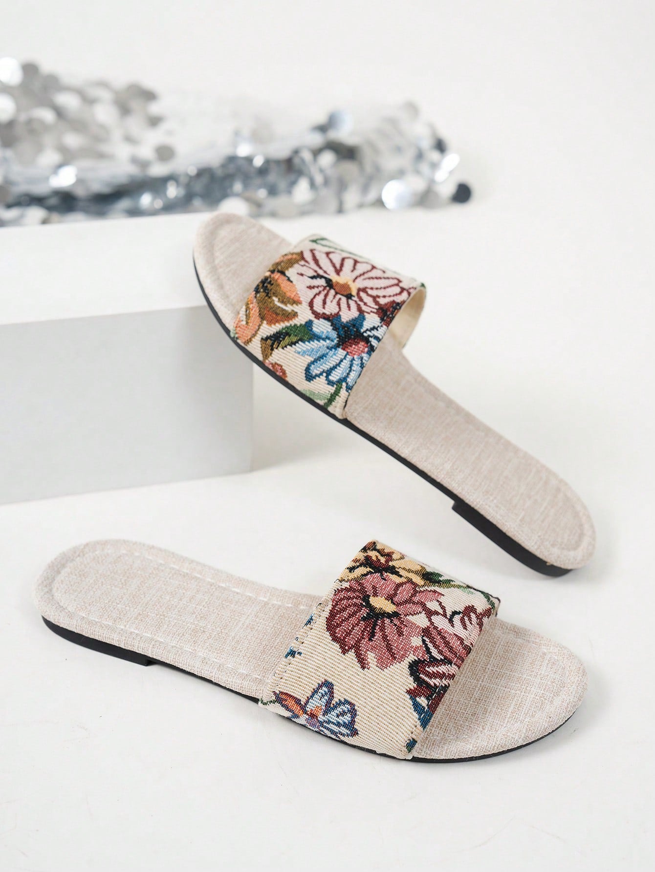 Women’s flat slide sandals featuring a floral printed strap and open toe design in a minimal style.