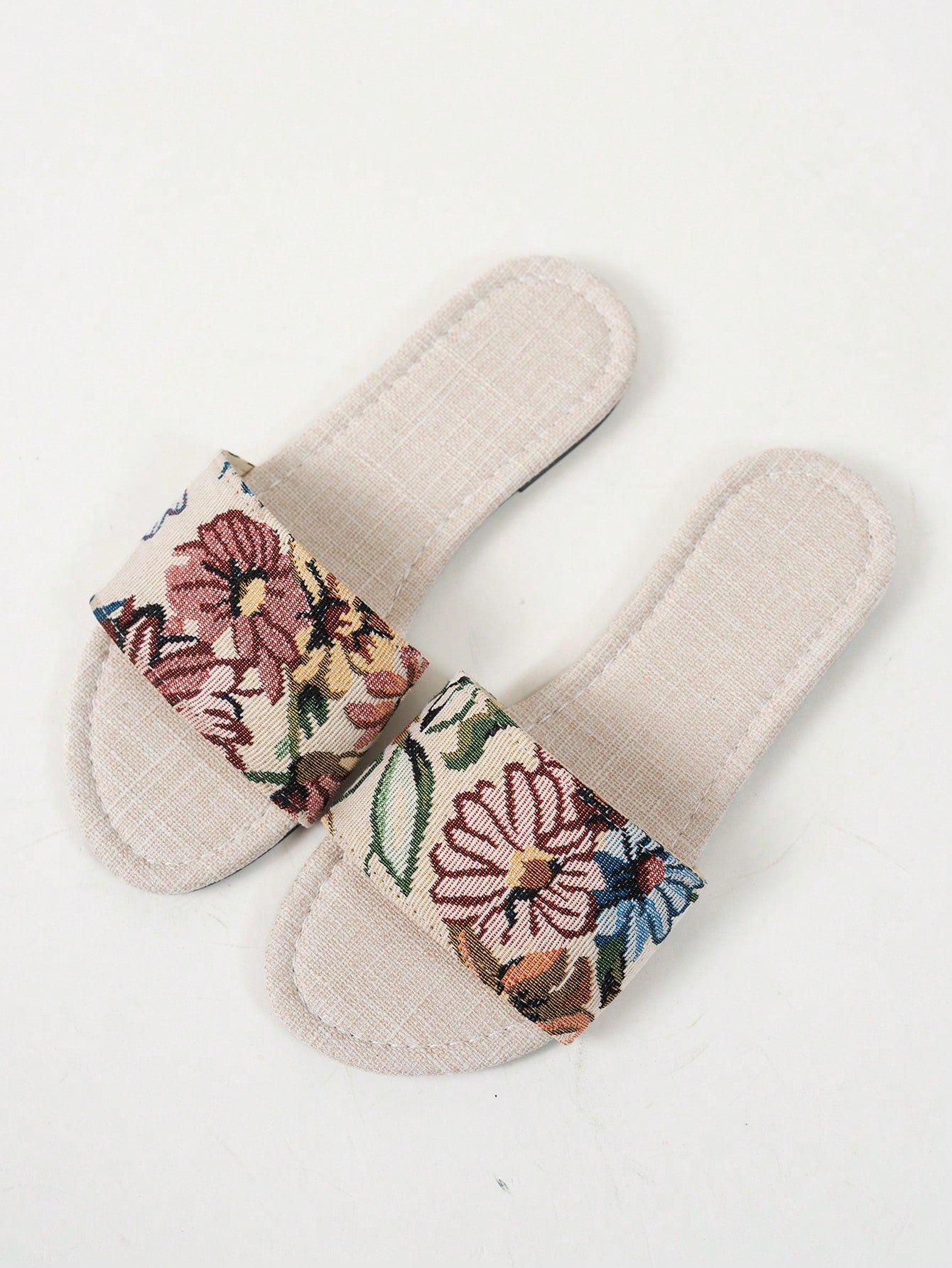 Women’s flat slide sandals featuring a floral printed strap and open toe design in a minimal style.