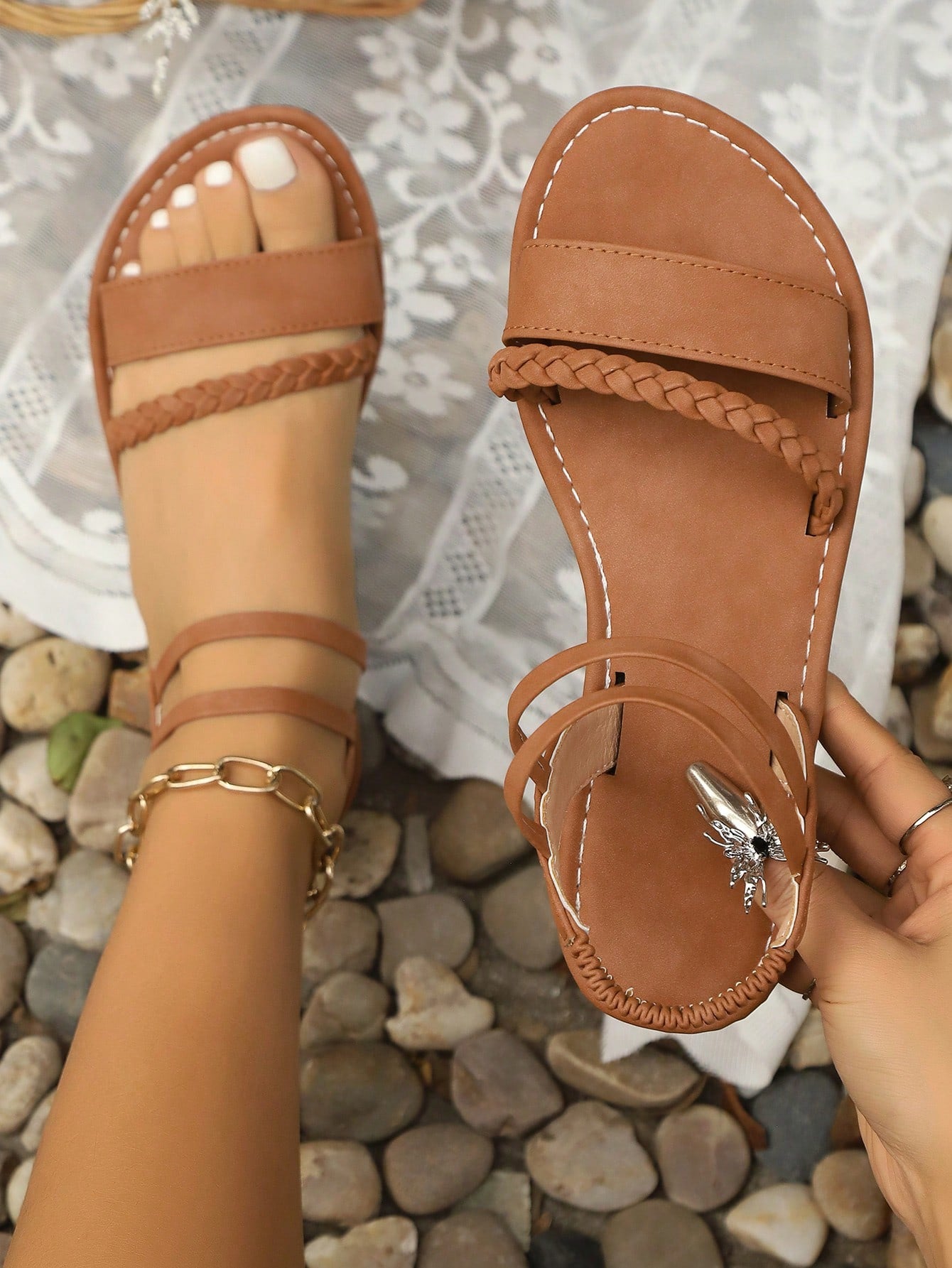 Girls brown slip-on flat Roman sandals with open toe, ankle strap, buckle and embroidery details, geometric pattern, and non-slip rubber outsole.
