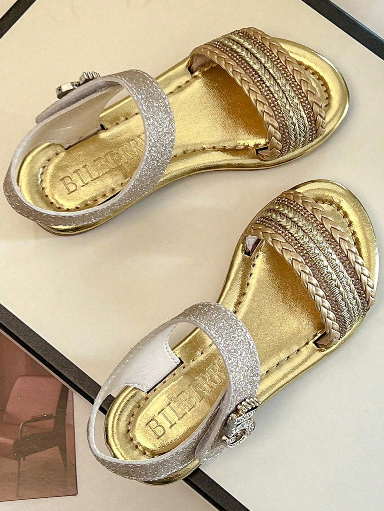 Pair of girls' pink open-toe flat sandals with ankle straps, buckle details, and a non-slip black rubber outsole.
