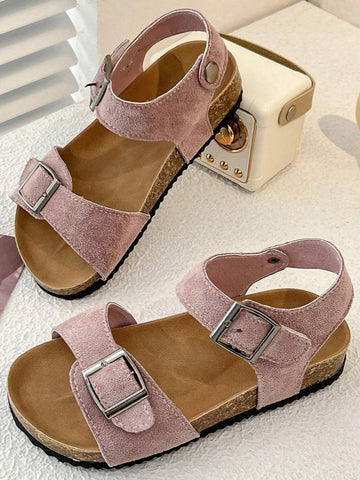 Pair of girls' pink open-toe flat sandals with ankle straps, buckle details, and a non-slip black rubber outsole.