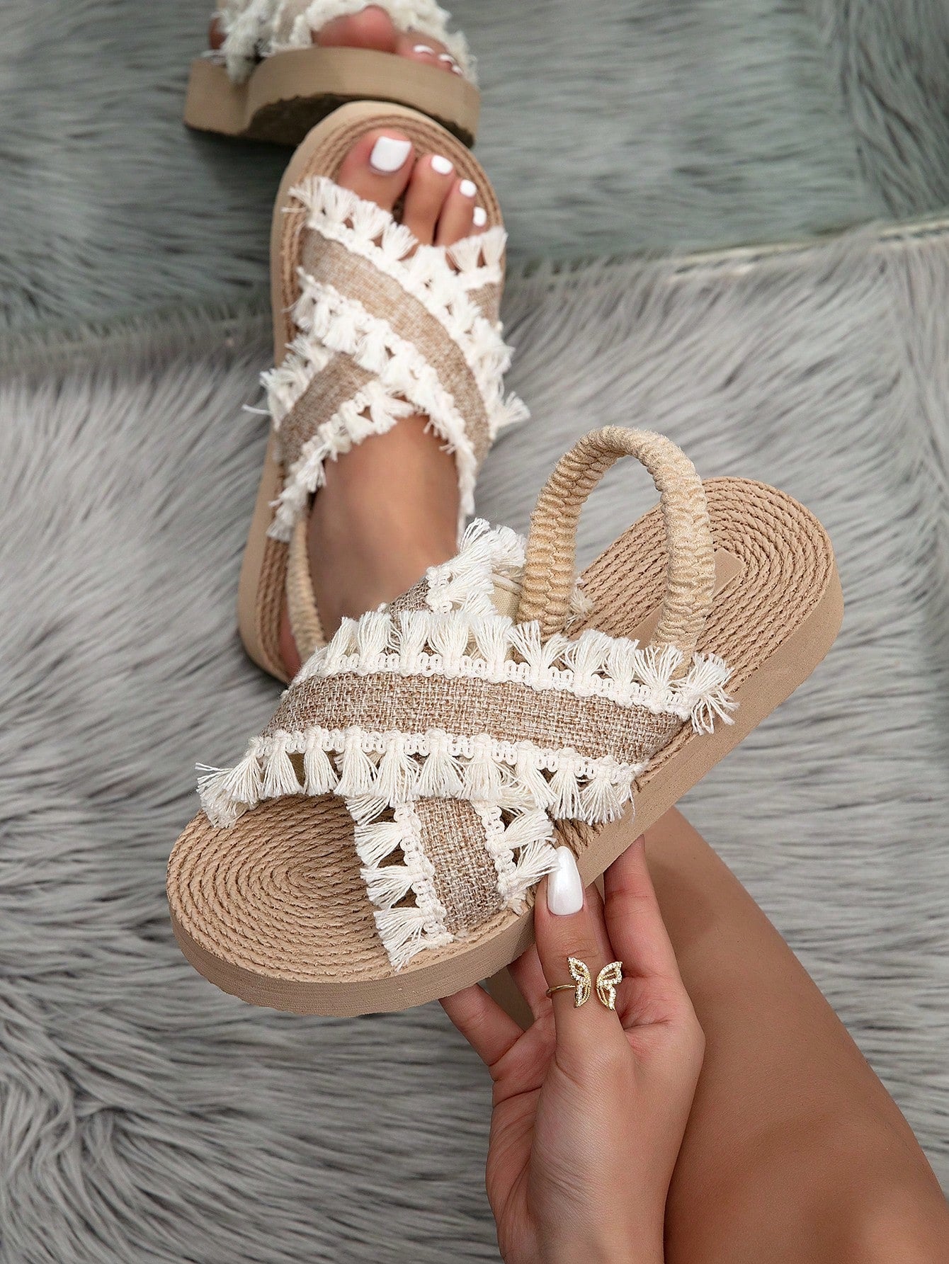 Women's open toe slip-on wedge sandals with criss cross straps and folk-custom styling, featuring raw hem, fringe, tassel, braid, and tape details.
