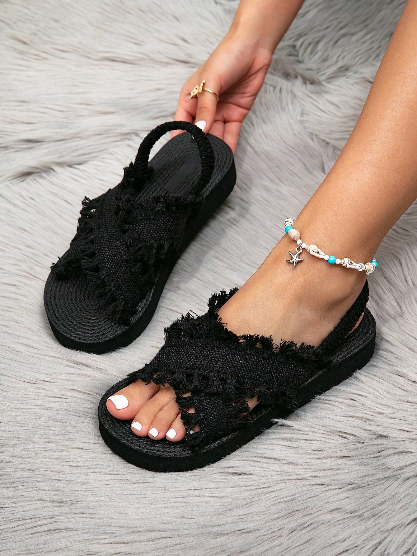 Women's open toe slip-on wedge sandals with criss cross straps and folk-custom styling, featuring raw hem, fringe, tassel, braid, and tape details.