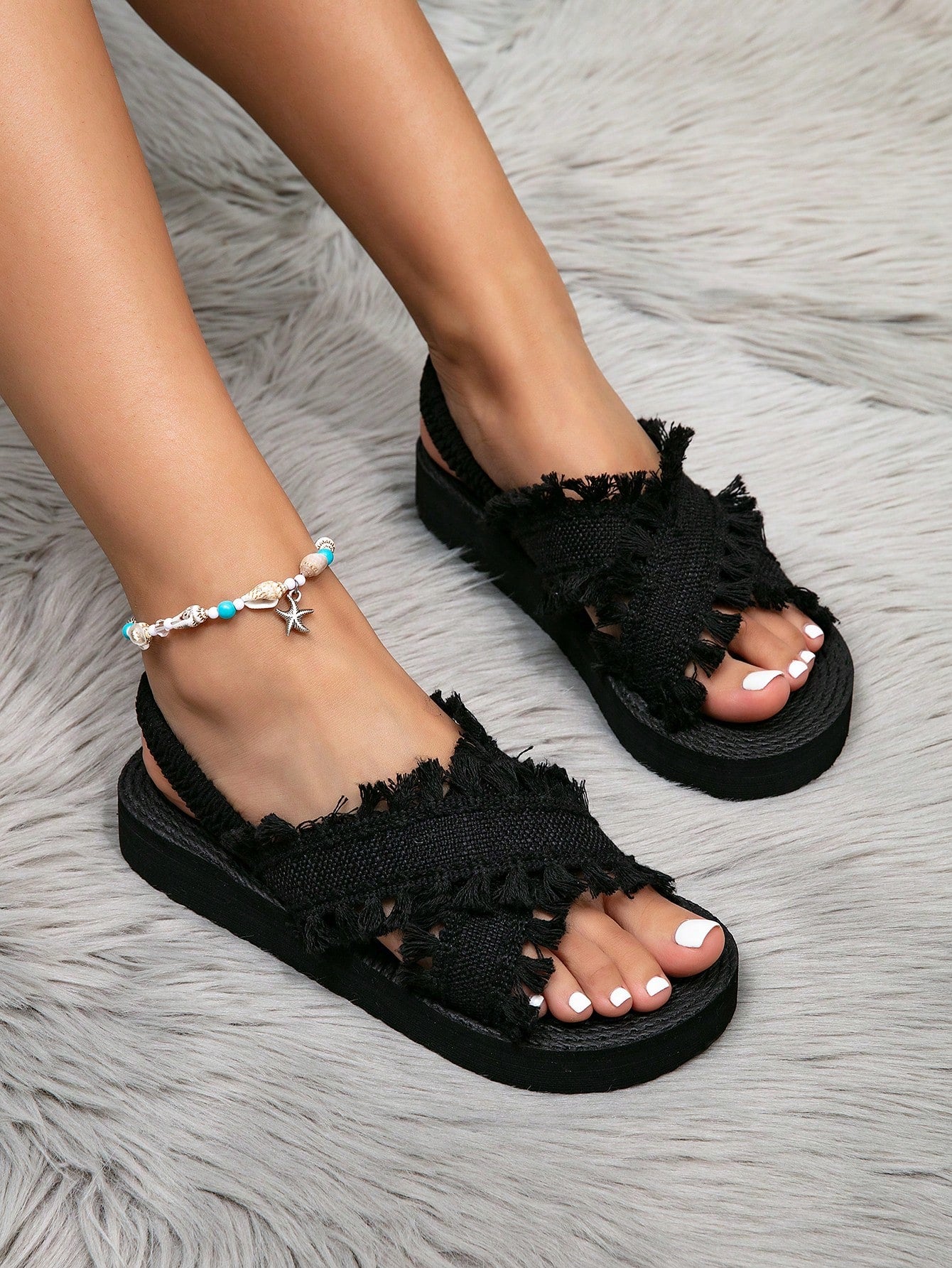 Women's open toe slip-on wedge sandals with criss cross straps and folk-custom styling, featuring raw hem, fringe, tassel, braid, and tape details.