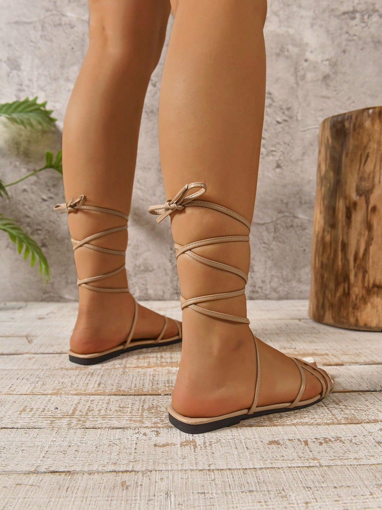 Women's tie-up flat sandals with a square open toe, woven criss-cross straps, and ankle wrap design, styled for beach and vacation wear.