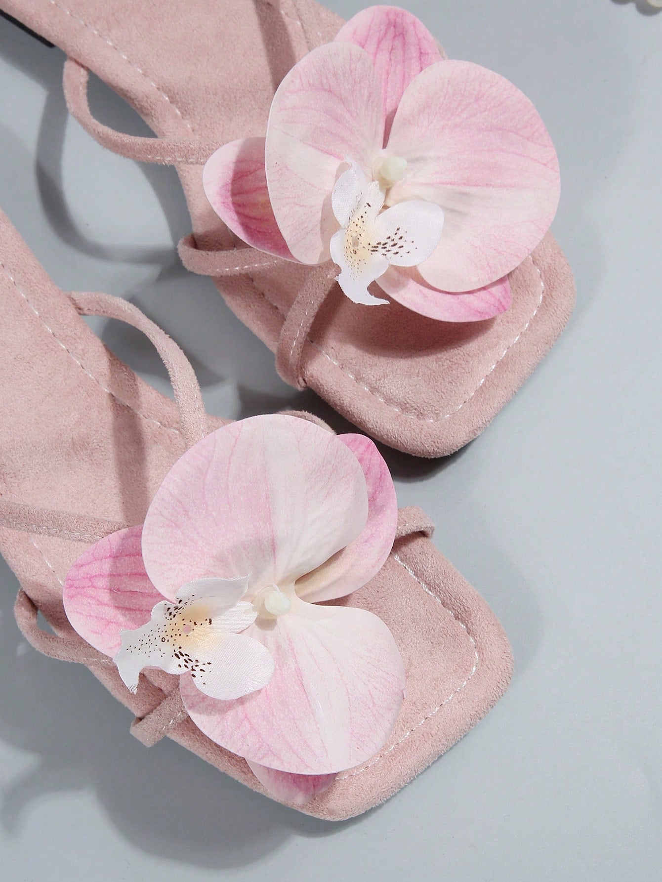Women's flat slide sandals with open toe, floral applique detail, and criss-cross straps, shown as casual vacation-style summer footwear.