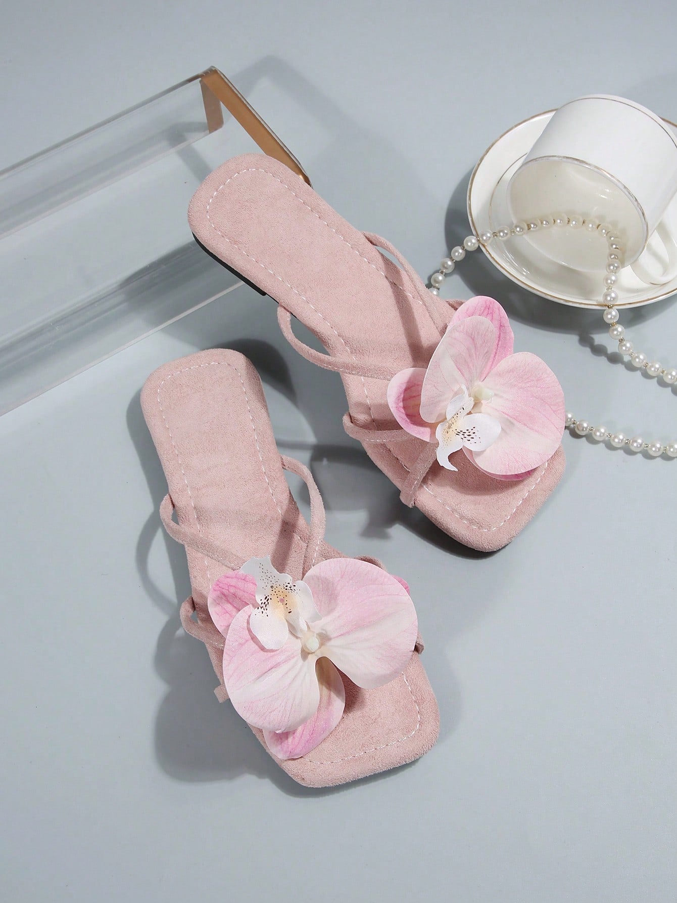 Women's flat slide sandals with open toe, floral applique detail, and criss-cross straps, shown as casual vacation-style summer footwear.