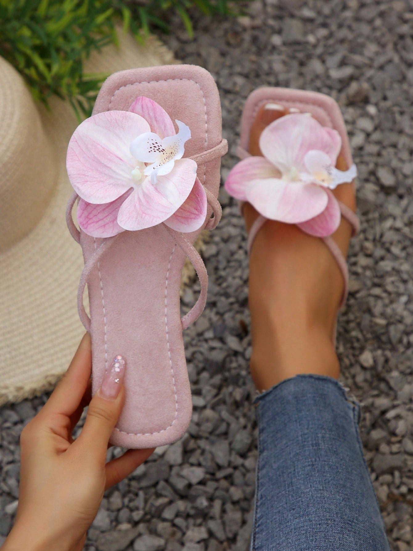 Women's flat slide sandals with open toe, floral applique detail, and criss-cross straps, shown as casual vacation-style summer footwear.