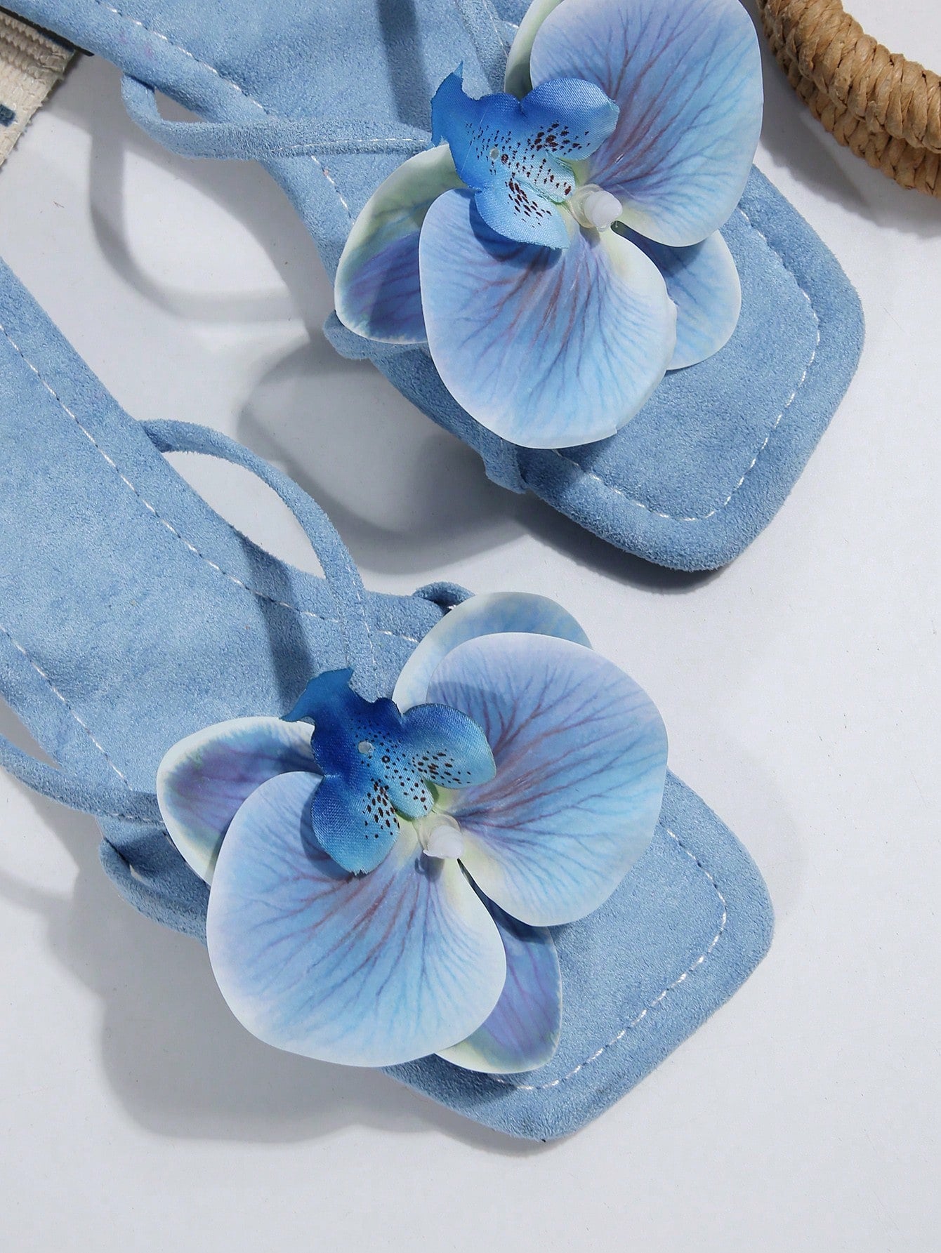 Women's flat slide sandals with open toe, floral applique detail, and criss-cross straps, shown as casual vacation-style summer footwear.