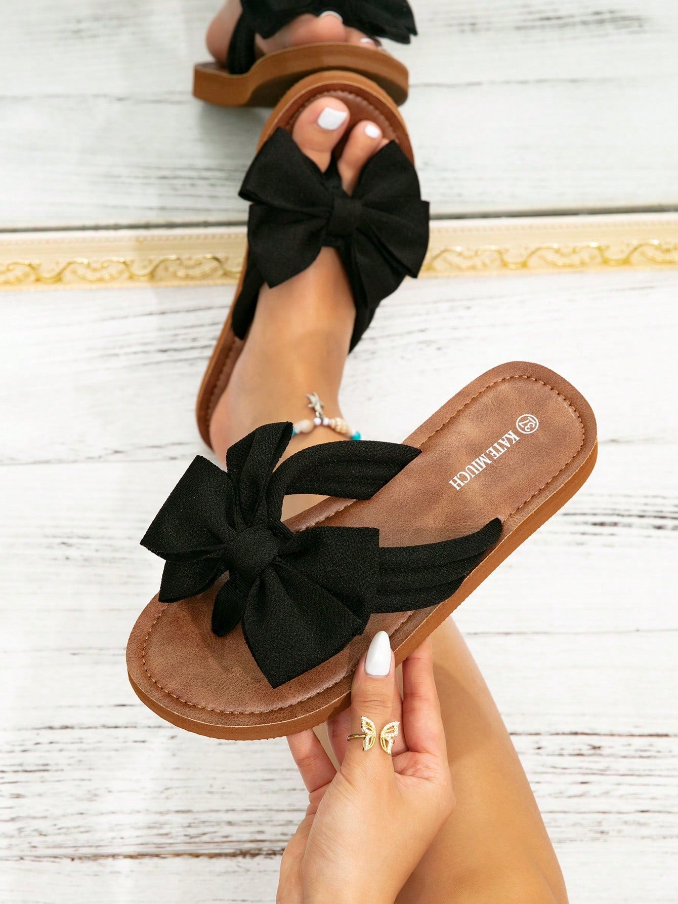Women's flat slide sandals with ruched fabric, bow accent, and fringe detail, suitable for outdoor vacation wear.