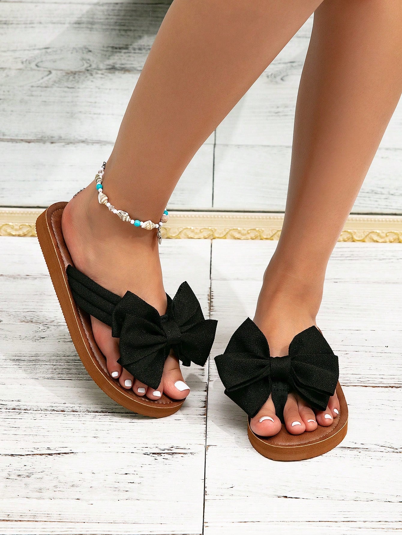 Women's flat slide sandals with ruched fabric, bow accent, and fringe detail, suitable for outdoor vacation wear.
