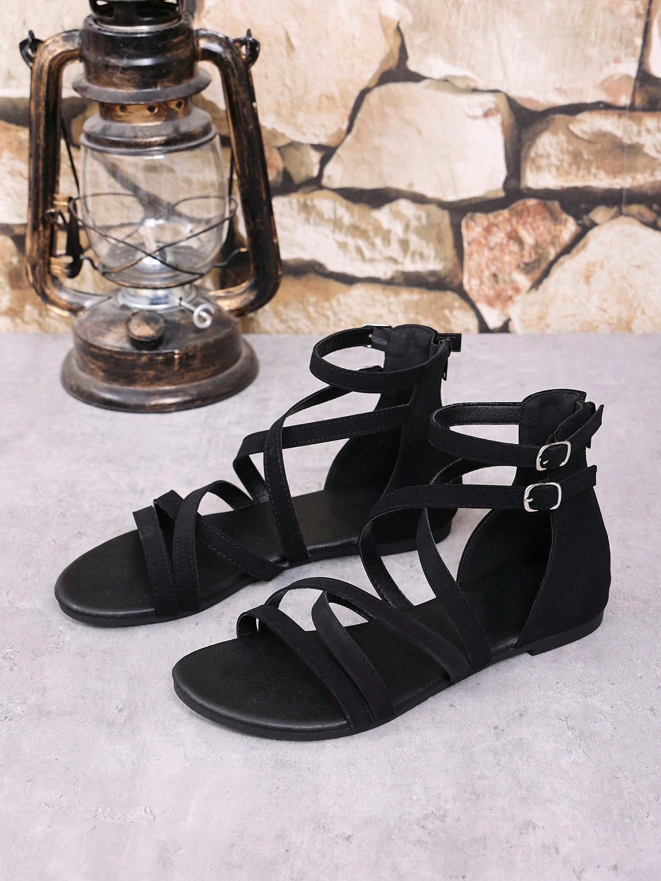 Women's black flat gladiator sandals with cross-over front straps, open toe design, and zipper back strap in a vintage casual beach style.
