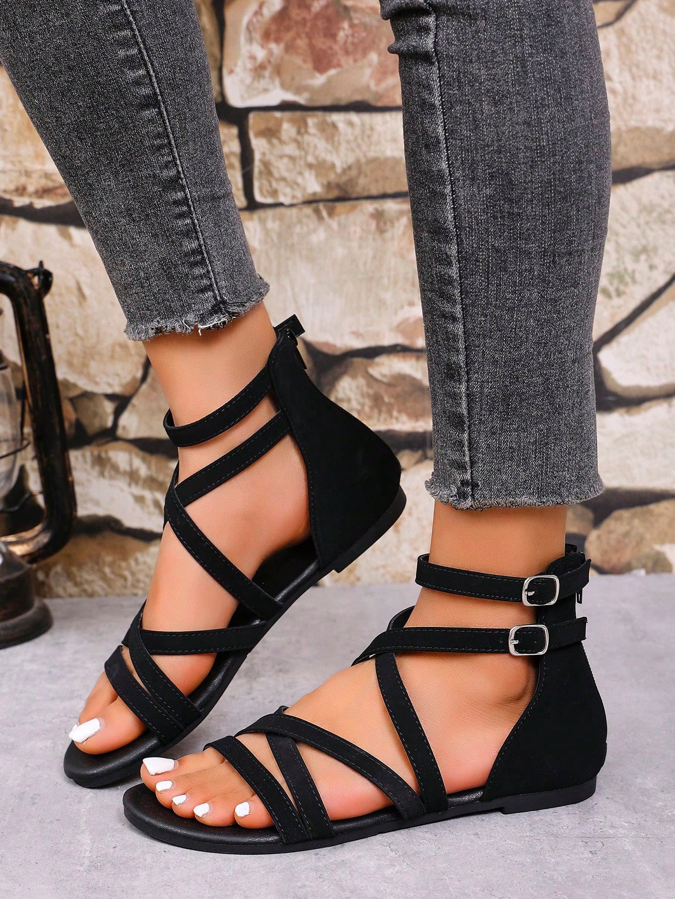 Women's black flat gladiator sandals with cross-over front straps, open toe design, and zipper back strap in a vintage casual beach style.