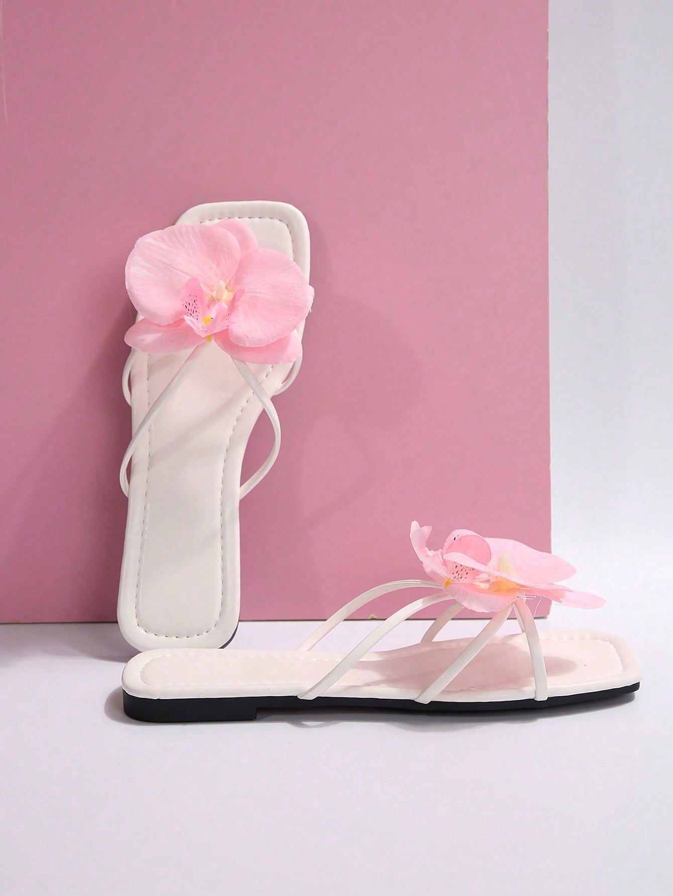 Women's flat slide sandals with open toe, floral applique detail, and criss-cross straps, shown as casual vacation-style summer footwear.