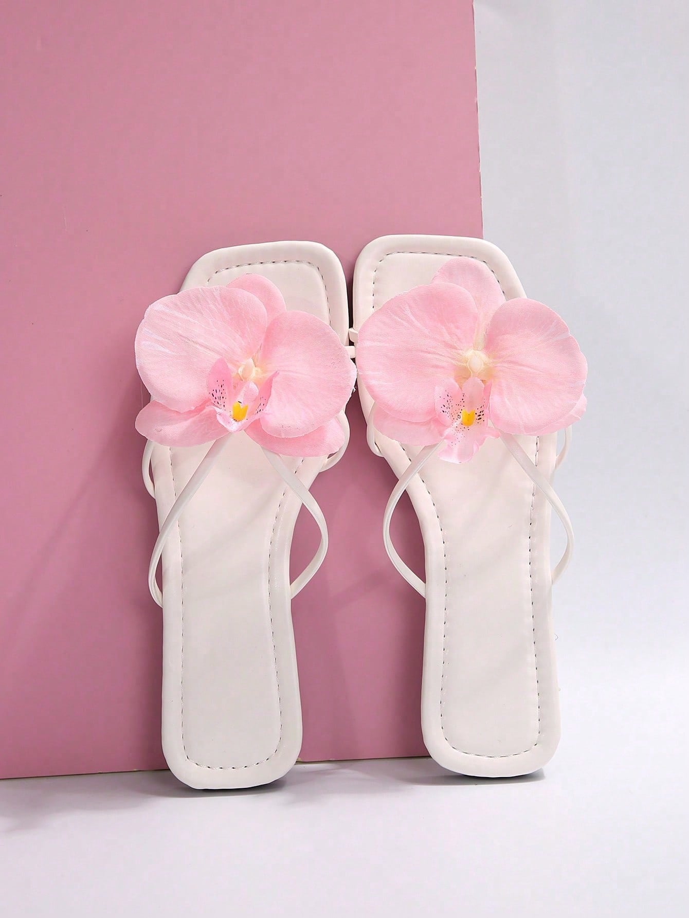Women's flat slide sandals with open toe, floral applique detail, and criss-cross straps, shown as casual vacation-style summer footwear.