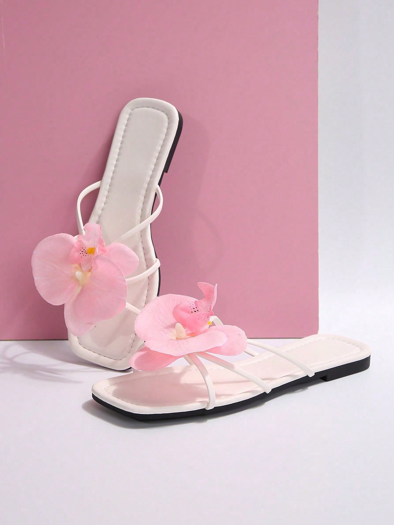 Women's flat slide sandals with open toe, floral applique detail, and criss-cross straps, shown as casual vacation-style summer footwear.