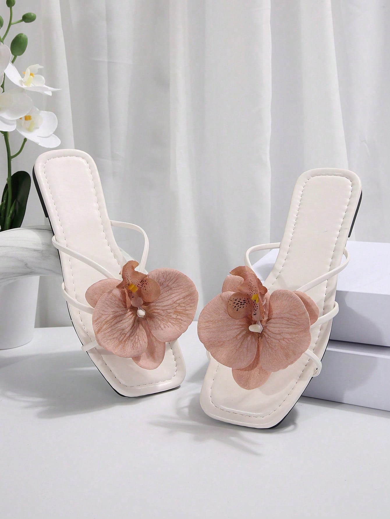 Women's flat slide sandals with open toe, floral applique detail, and criss-cross straps, shown as casual vacation-style summer footwear.