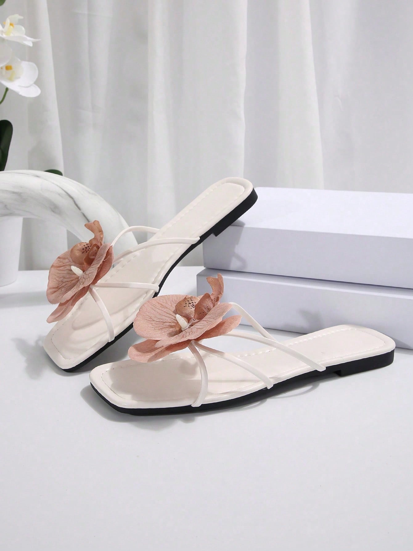 Women's flat slide sandals with open toe, floral applique detail, and criss-cross straps, shown as casual vacation-style summer footwear.