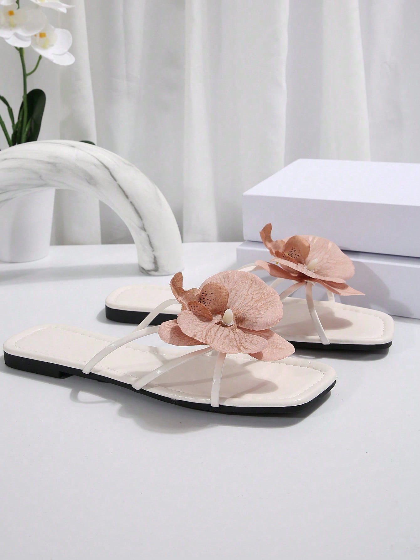 Women's flat slide sandals with open toe, floral applique detail, and criss-cross straps, shown as casual vacation-style summer footwear.