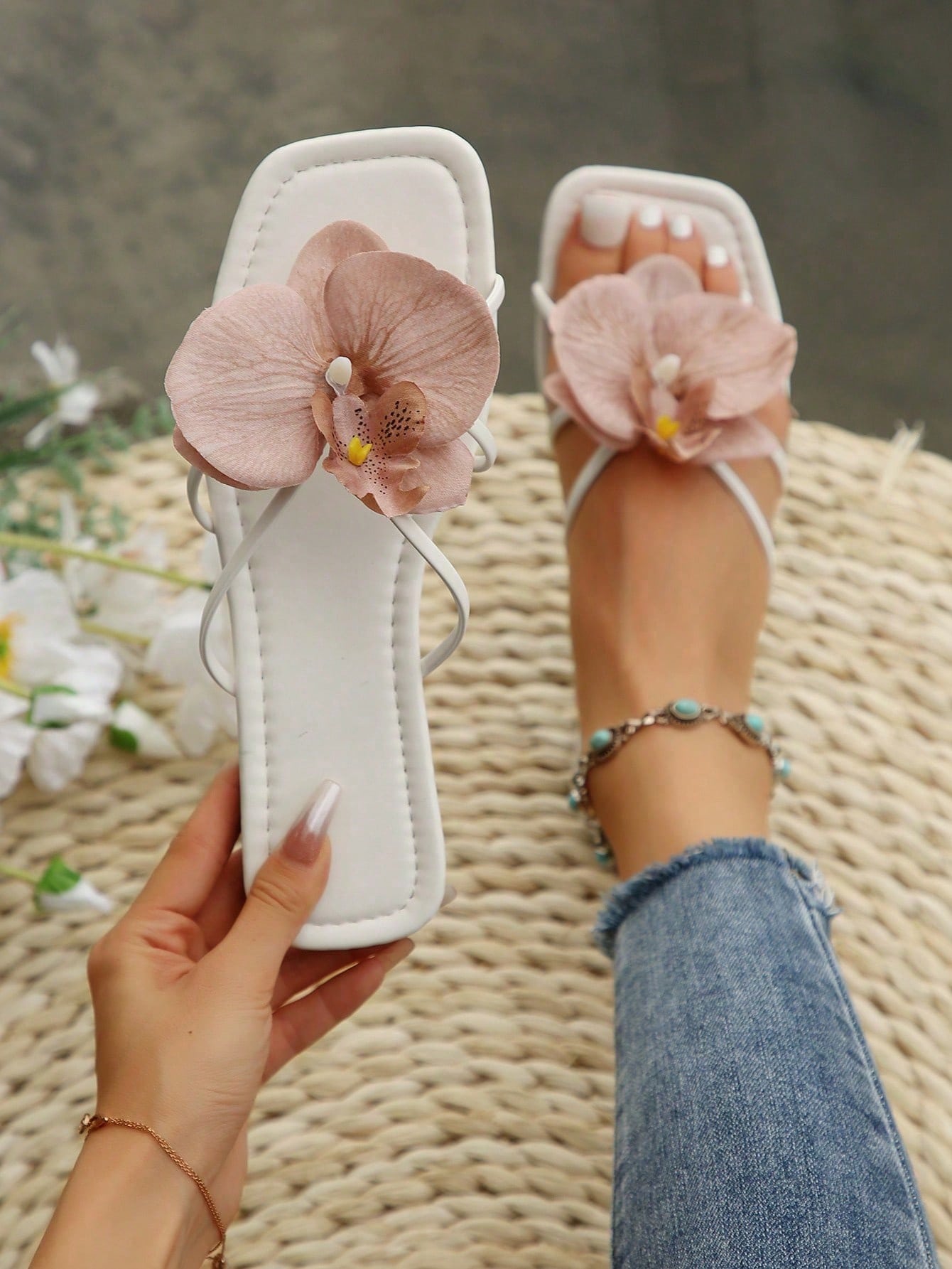 Women's flat slide sandals with open toe, floral applique detail, and criss-cross straps, shown as casual vacation-style summer footwear.