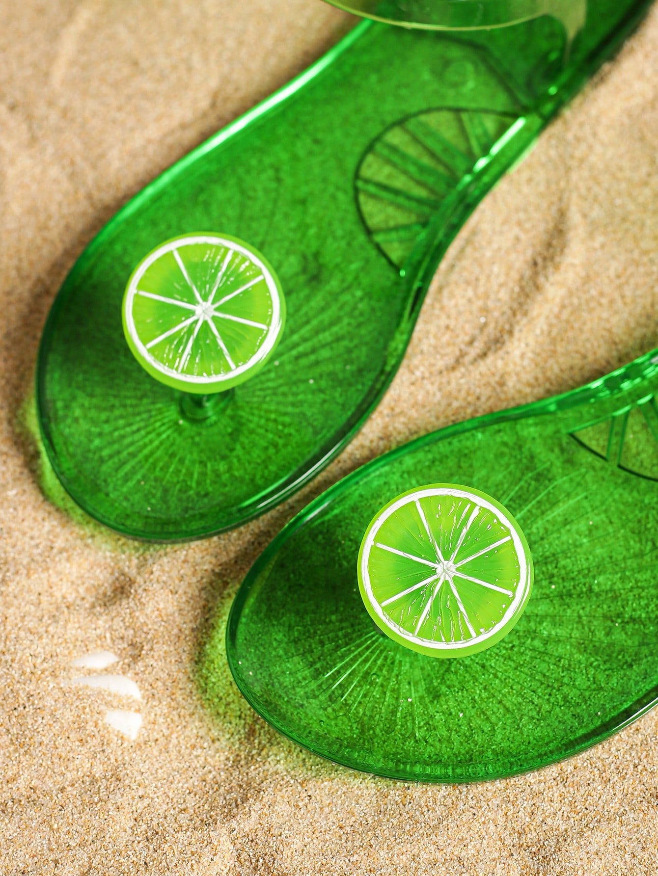 Green women’s clear jelly flat slide sandals with fruit graphic decoration and toe post design, suitable for beach, vacation, and casual outdoor wear.