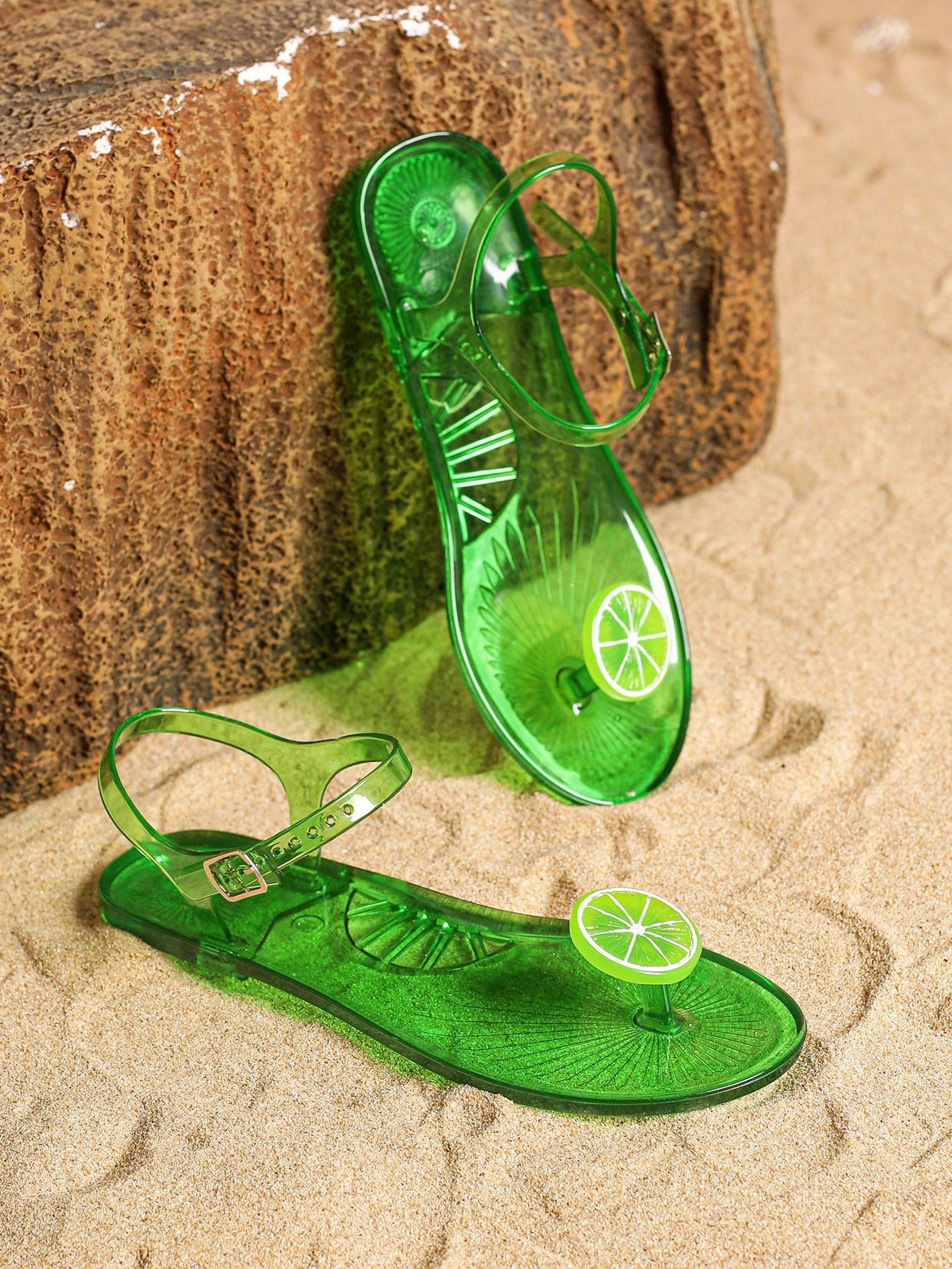 Green women’s clear jelly flat slide sandals with fruit graphic decoration and toe post design, suitable for beach, vacation, and casual outdoor wear.