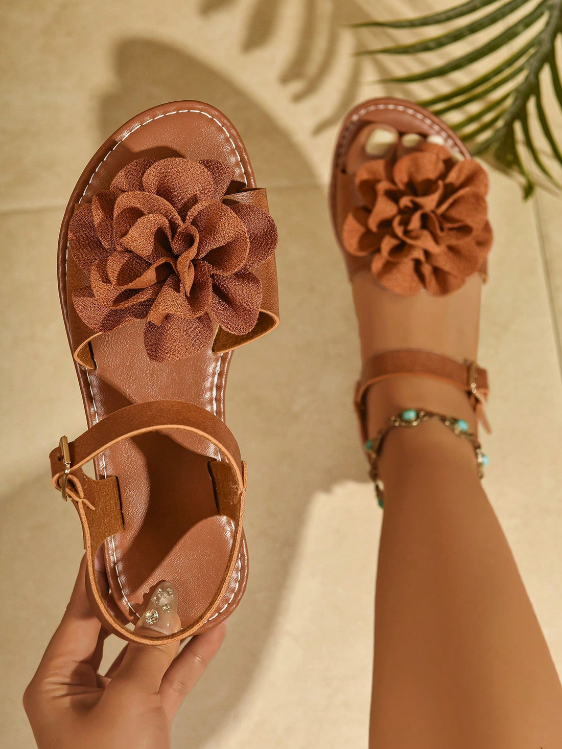 Women's wide width flat thong sandals in brown with toe post, buckle detail, and elastic strap, designed for comfortable beach and casual summer wear.