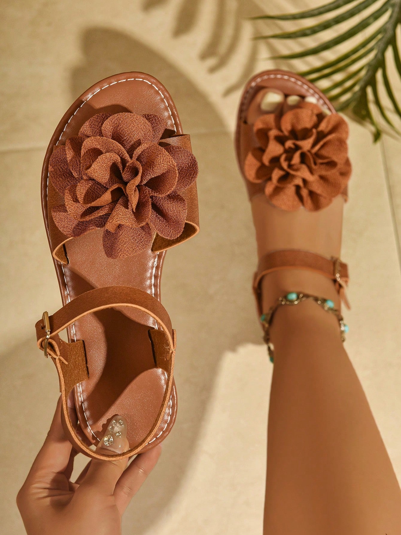 Women's wide width flat thong sandals in brown with toe post, buckle detail, and elastic strap, designed for comfortable beach and casual summer wear.