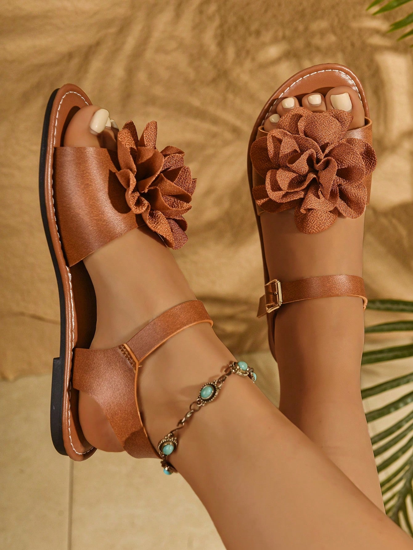 Women's wide width flat thong sandals in brown with toe post, buckle detail, and elastic strap, designed for comfortable beach and casual summer wear.