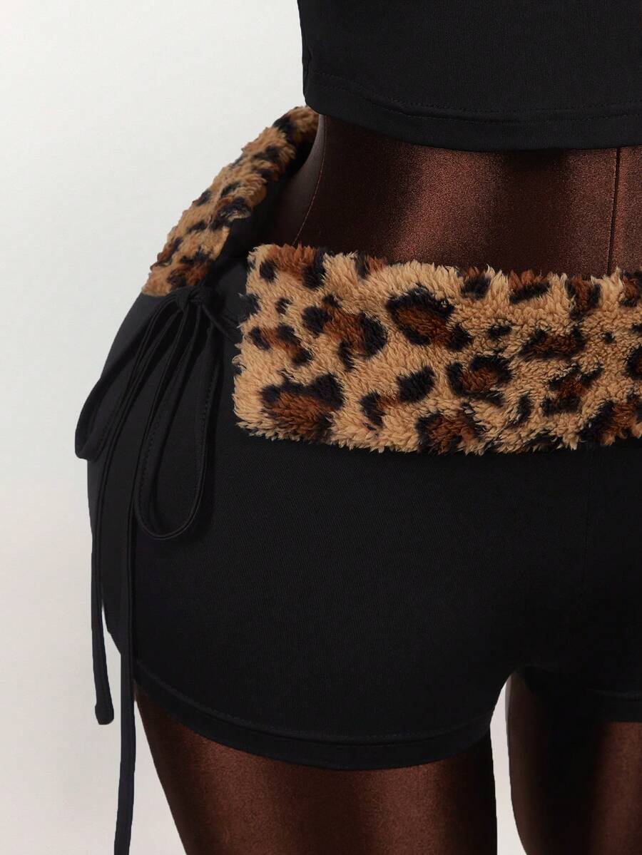 Women's black leopard print two-piece set with strapless bandeau crop top, knot and lace-up details, and matching mini shorts.