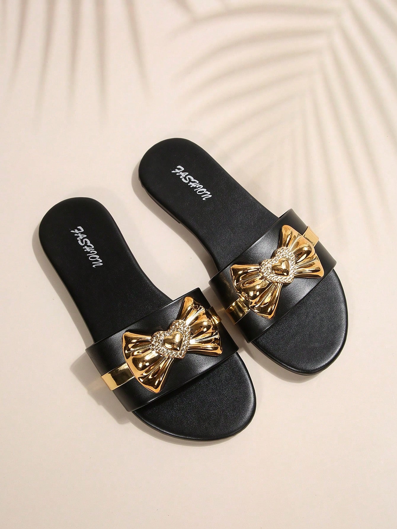 Pair of women's black flat slide sandals featuring rhinestone embellishments, metal accents, and a gold-strip detail on the upper, with an open-toe slip-on design.