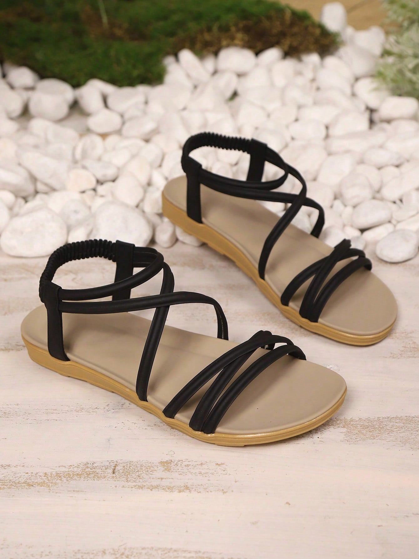 Women's beige flat sandals with criss cross straps, ankle strap, and open toe.