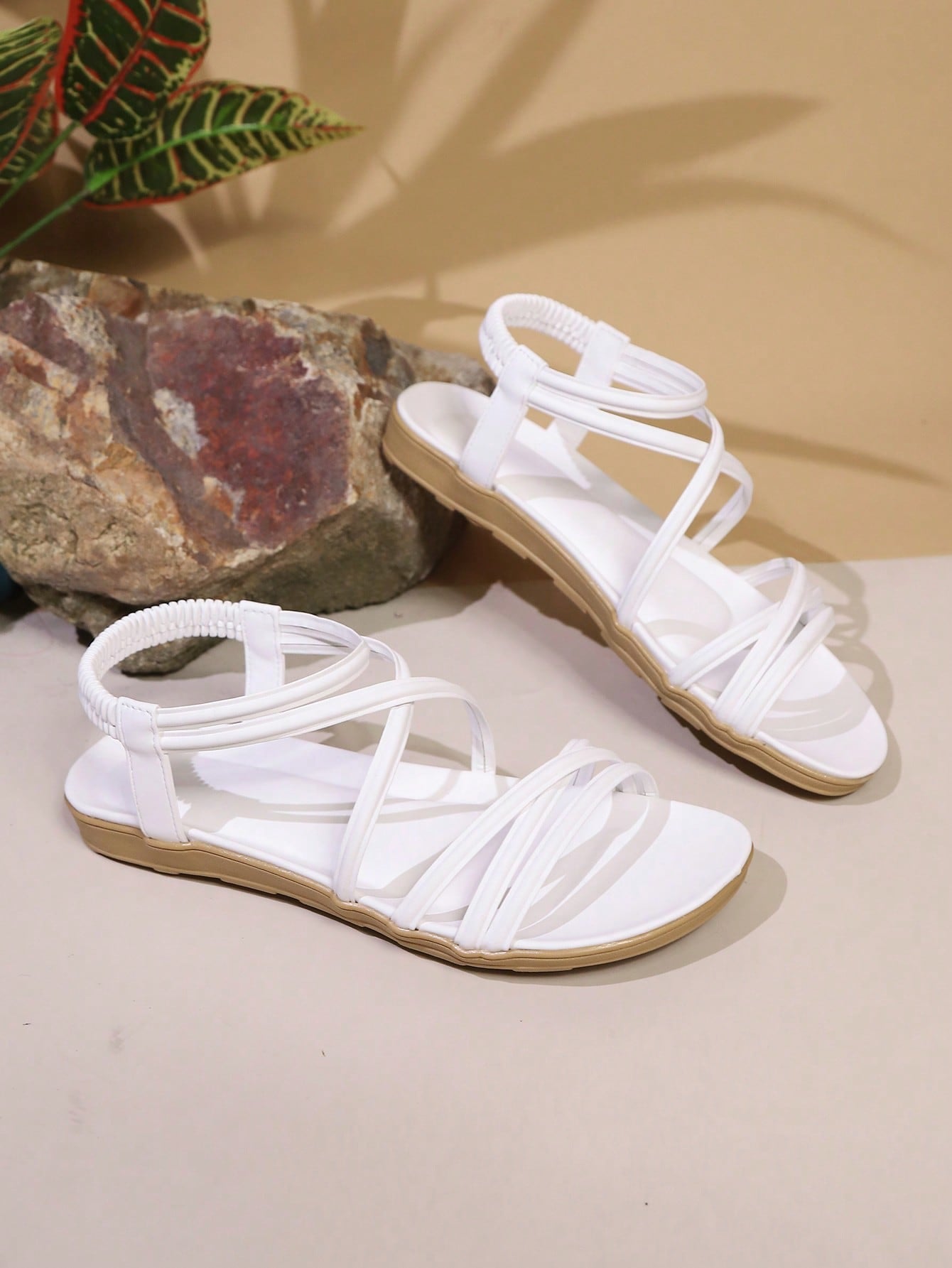 Women's beige flat sandals with criss cross straps, ankle strap, and open toe.