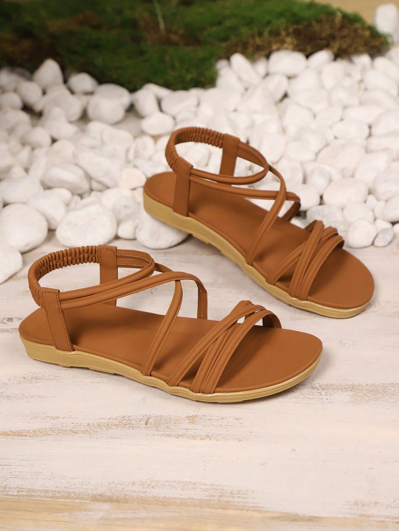 Women's beige flat sandals with criss cross straps, ankle strap, and open toe.